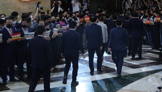 항의하는 통합당 외면하는 민주당21대 국회 첫 상임위원장 선출을 위한 본회의가 열린 15일 항의 구호를 외치는 미래통합당 의원들 사이로 더불어민주당 의원들이 본회의장에 입장하고 있다.   연합뉴스